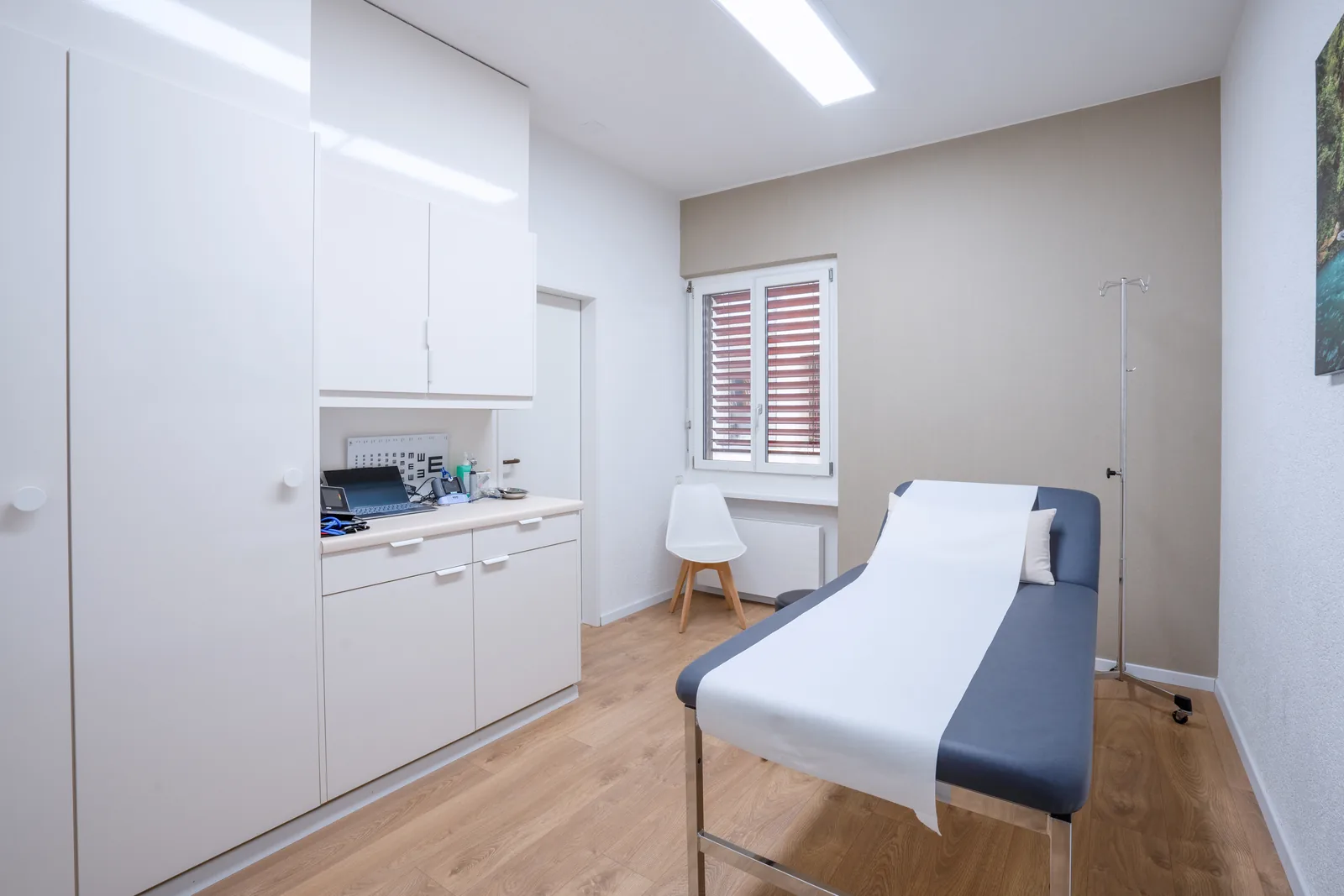 Behandlungszimmer mit Untersuchungsliege und Schrankzeile